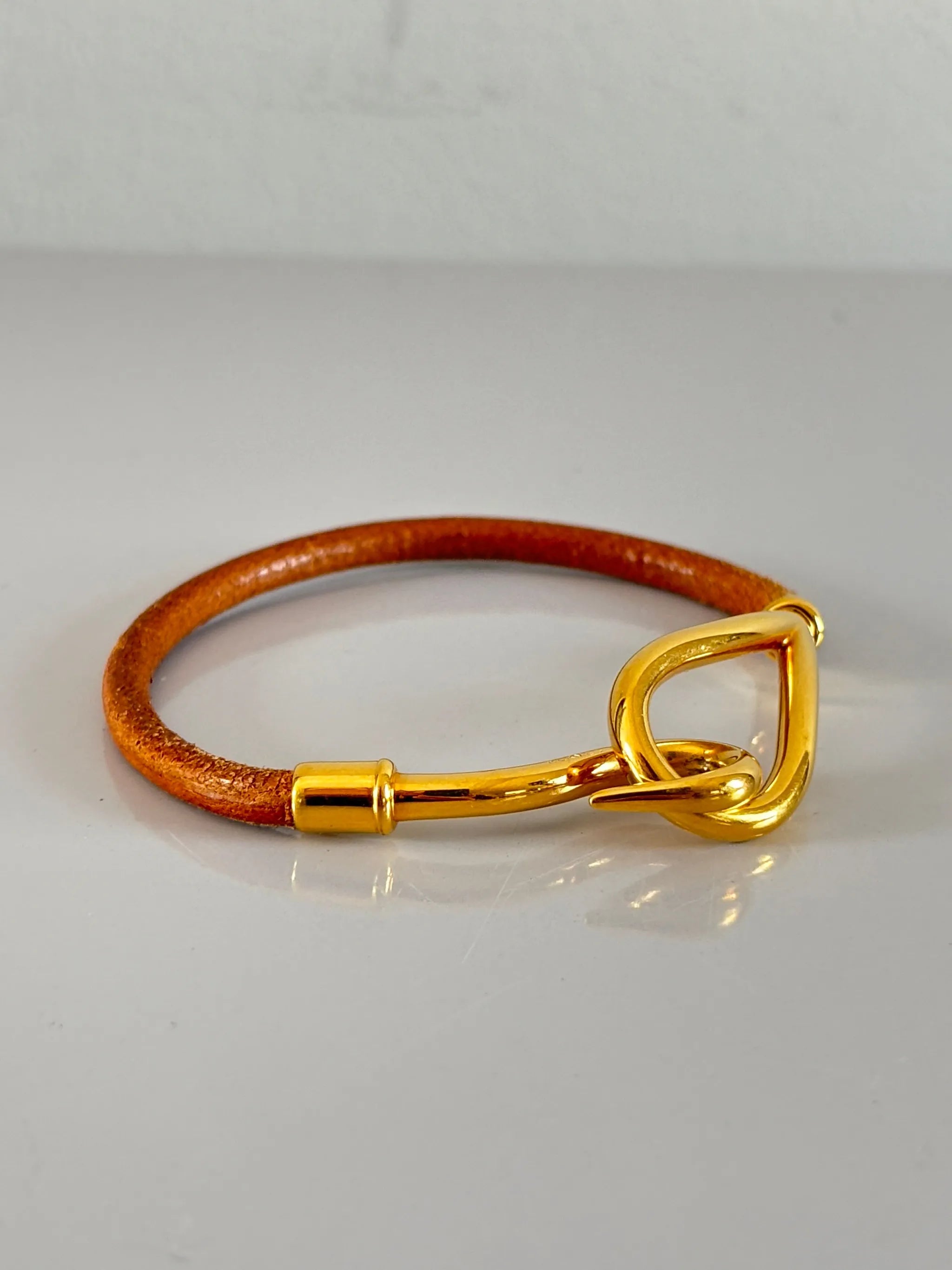 Bracelet jumbo en cuir naturel avec fermoir en métal doré, élégant et classique.